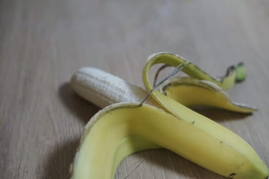 ripe fresh half peeled yellow bananas skin on wooden table background fruits healthy snack vitamin eat immune colorful organic . High quality photo