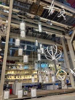 Castle Rock, Colorado, USA-Narch 15, 2023-A variety of modern pendant light fixtures hanging from a display rack in a lighting store The lights have unique designs including rectangular glass pendants geometric shapes and LED accents The store shelves in the background showcase additional lighting options creating a well-lit retail environment