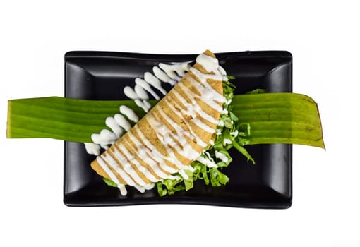 Taco xochimilco friend with masa dough lettuce and sour cream on black plate isolated on white background