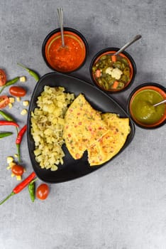Mexican omelet with potato on black plate with latin american food on gray background