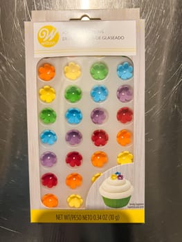 Castle Rock, Colorado, USA-May 7, 2023-A package of Wilton icing decorations featuring colorful sugar flowers designed for decorating cupcakes cakes and other baked goods The packaging includes an image of a decorated cupcake as a serving suggestion The product is displayed against a stainless steel background