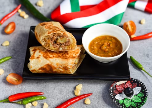 Mexican burrito with beef, french fries and cheese served with sauce borracha