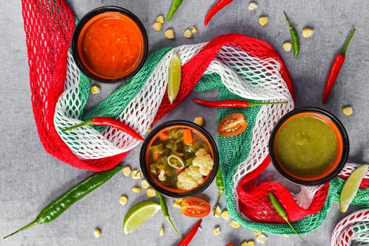 Three mexican sauces with vegetables and mexican flag on gray background