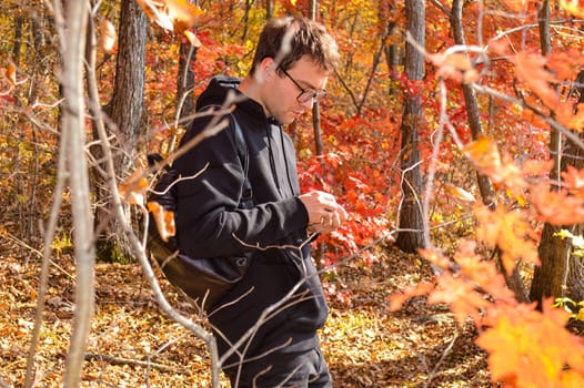 Portrait of Russian young man walking in autumn forest and exploring nature