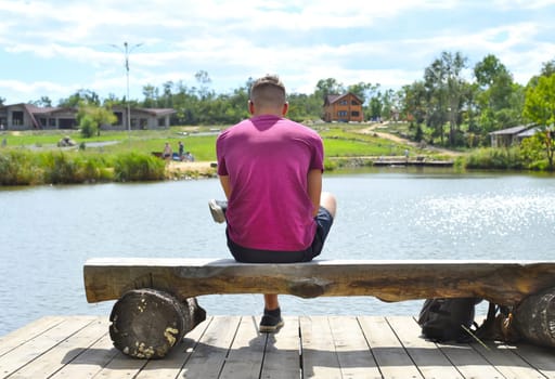 Young man sitting on a bench against lake