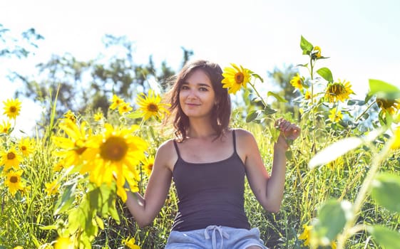 Young girl sitting in a field with sunflowers