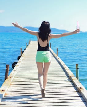 45 years old Russian woman with lemonad running on pier against Japanese sea