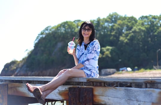 45 years old Russian woman drinking lemonad and sitting on pier45 years old Russian woman drinking lemonad and sitting on pier