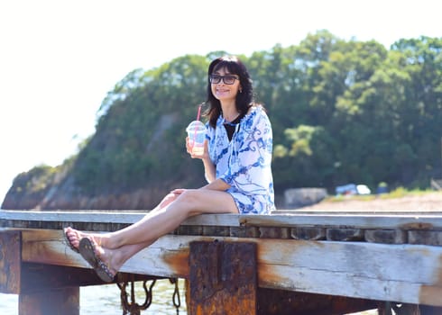 45 years old Russian woman drinking lemonad and sitting on pier45 years old Russian woman drinking lemonad and sitting on pier