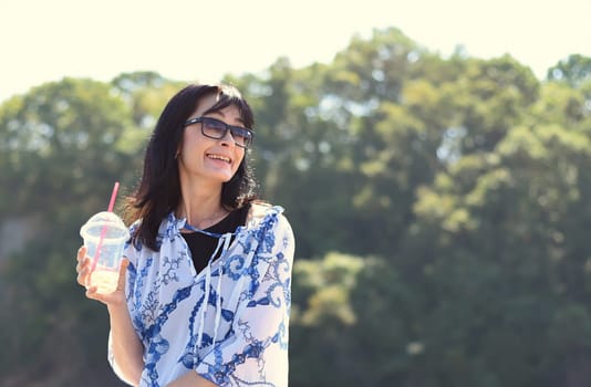 45 years old Russian woman drinking lemonade and sitting on pier