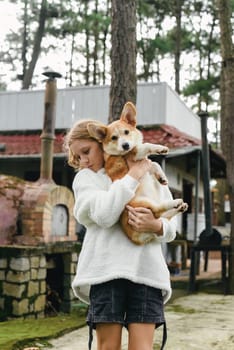 Little cute girl holding her corgi dog on an autumn day