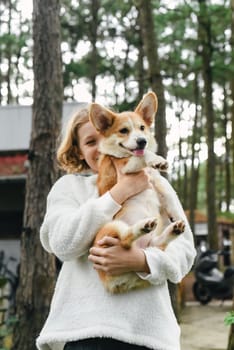 Little cute girl holding her corgi dog on an autumn day