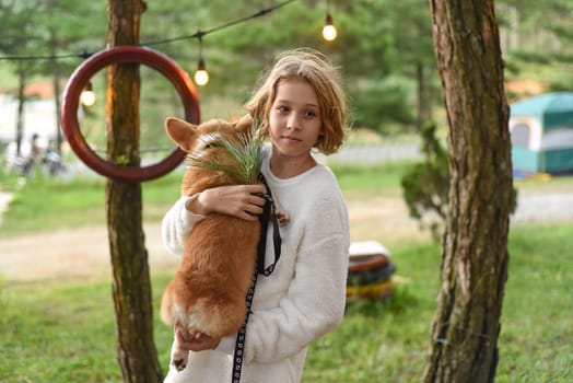 Little cute girl holding her corgi dog on an autumn day
