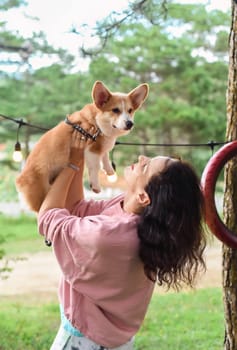 Young woman hugging her corgi dog in the forest