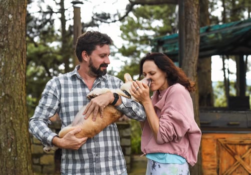 Happy bearded man and woman holding their welsh corgi dog and smiling