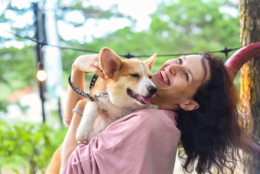 Young woman hugging her corgi dog in the forest