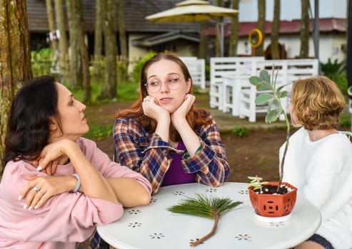 Mother and her two daughters sitting by the table and talking together