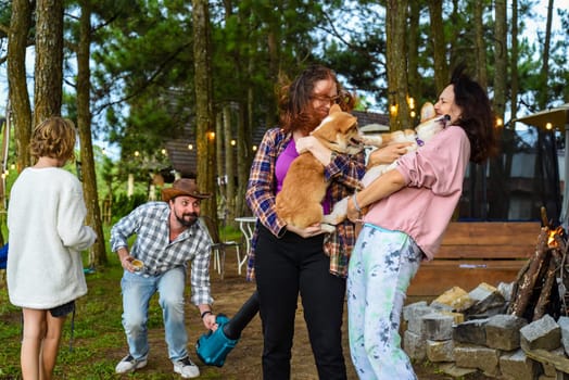 Funny family moment with father using garden blower for teasing his wife and daughter holding dogs