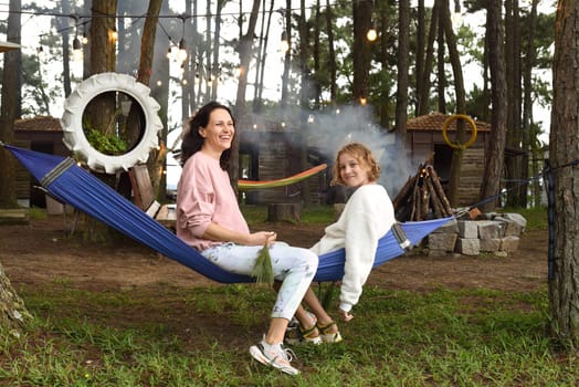 Mother and her daughter fooling around and sitting in hammock in the eveningMother and her daughter fooling around and sitting in hammock in the evening
