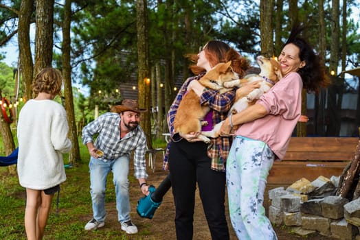 Funny family moment with father using garden blower for teasing his wife and daughter holding dogs