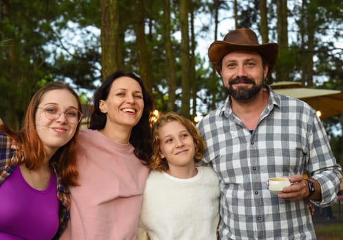 Family members father, mother and two daughters laughing in camping in the forest