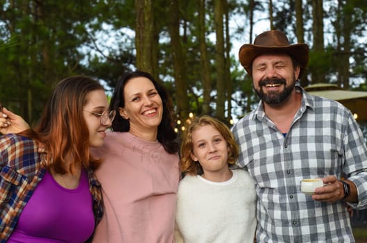 Family members father, mother and two daughters laughing in camping in the forest
