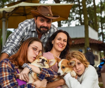 Family members father, mother and two daughters with corgi dogs in the forest