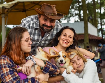 Family members father, mother and two daughters with corgi dogs in the forest