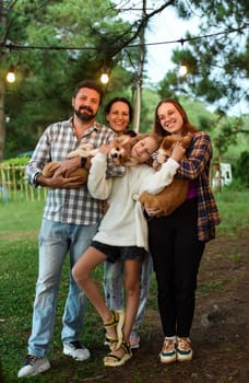Family members father, mother and two daughters with corgi dogs in the forest