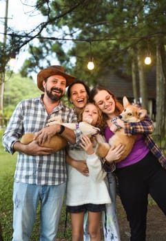 Family members father, mother and two daughters with corgi dogs in the forest