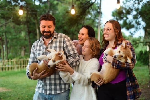 Family members father, mother and two daughters with corgi dogs in the forest