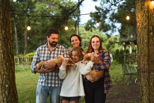 Family members father, mother and two daughters with corgi dogs in the forest