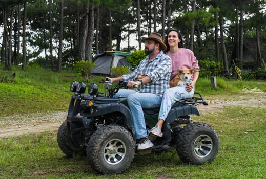 Portrait of young married couple sitting on a quad bike in the forest