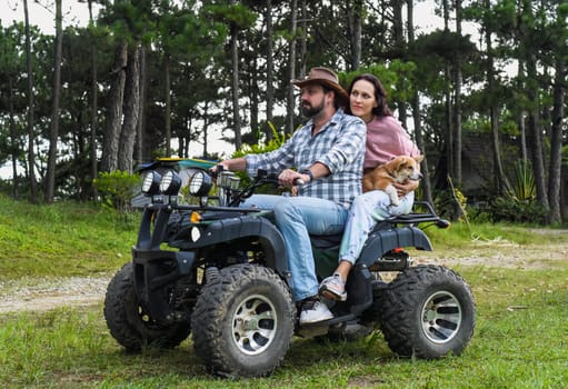 Portrait of young married couple sitting on a quad bike in the forest