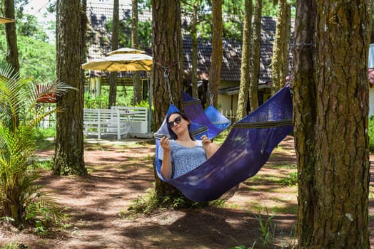 Young brunette woman resting in hammock in forest