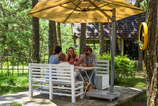 Family members father, mother and two daughters sit in alcove in park