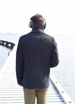 Lonely man with headphones standing on a pier and looking at Japanese sea