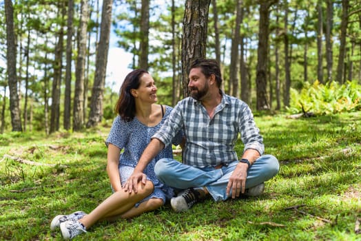 Young married couple kissing and sitting in the forest on a sunny day