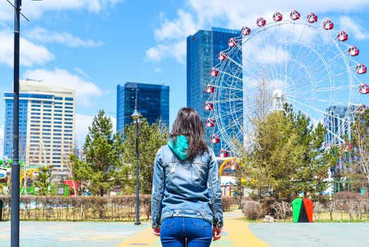 Young woman standing and looking at the amusement park