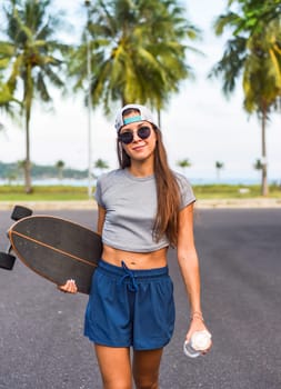 Young beautiful woman in a cap standing and holding skateboard with a cool face