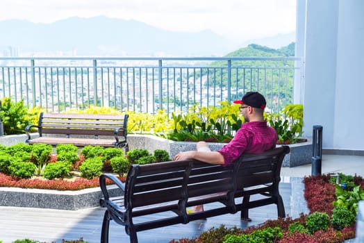 Young tourist man resting on the bench and looking at Nha Trang city
