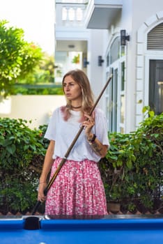 Young blond woman playing billiards in the backyard