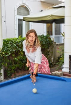 Young blond woman playing billiards in the backyard