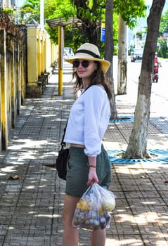 Young tourist woman holding a bag with fruit and vegetables after shopping in Nha Trang Vietnam