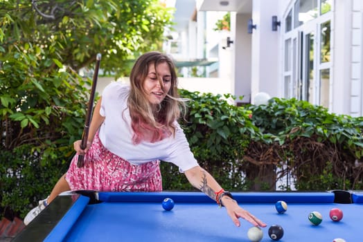 Young blond woman playing billiards in the backyard