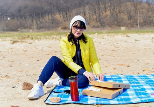 Russian 45 year old woman going to eat pizza while sitting on the beach