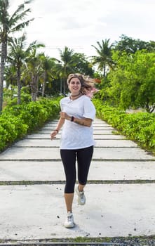 Beautiful woman in sport clothes running into a camera