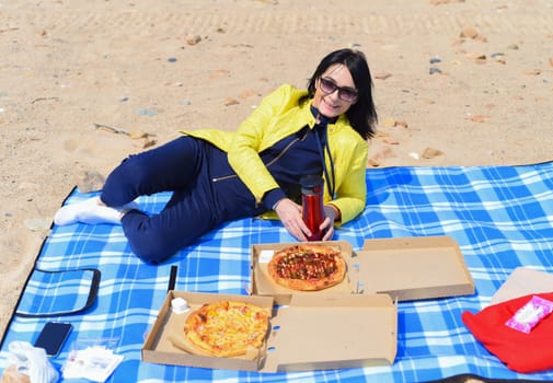 Russian 45 year old woman going to eat pizza while sitting on the beach