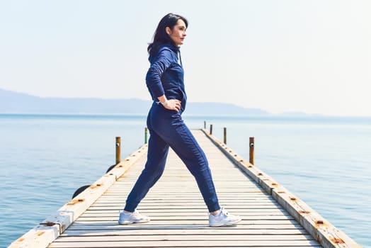 45 y.o. Russian woman squatting  on a wooden pier by the Japanese sea