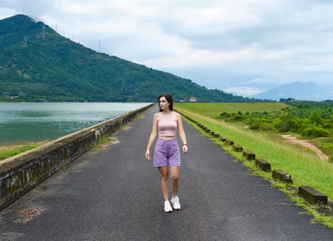 Young russian woman traveler with depressed and sad face walking alone near lake and mountains in Khanh Hoa Province, Vietnam